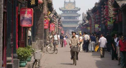 China- Bustling historic street scene with locals, lanterns and bicycles in a traditional Chinese town. 