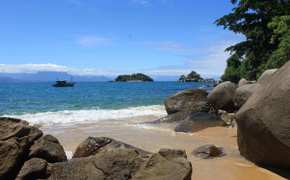 Small boat anchored off a secluded beach with rocky shoreline on Ilha Grande. 